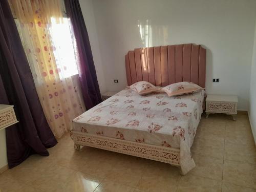 a bedroom with a bed with a wooden headboard at CHEZ ALAA Kelibia in Kelibia