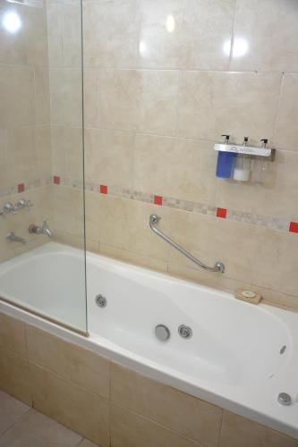 a bath tub in a bathroom with a glass door at Hotel Termal Rio Hondo in Termas de Río Hondo