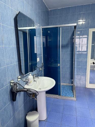 a blue tiled bathroom with a sink and a shower at Hostel Villa EFES Private Rooms in Tirana