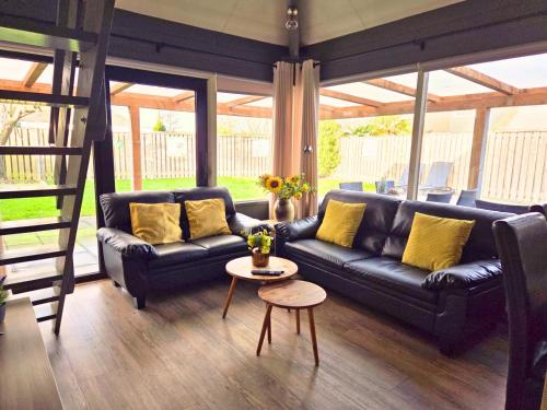 a living room with a black leather couch and a table at Zeeuwse Luwte in Stavenisse