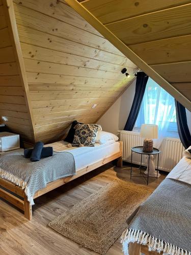 two beds in a room with a wooden ceiling at Apartamenty nad Przełomem Białki Apartments in a nature reserve Przełom Białki in Nowa Biała