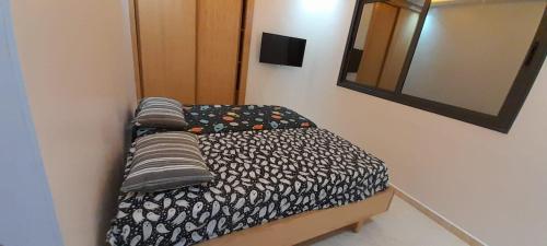 a small bedroom with a bed and a mirror at Maghrib ARABI OULED OUJIH in Kenitra