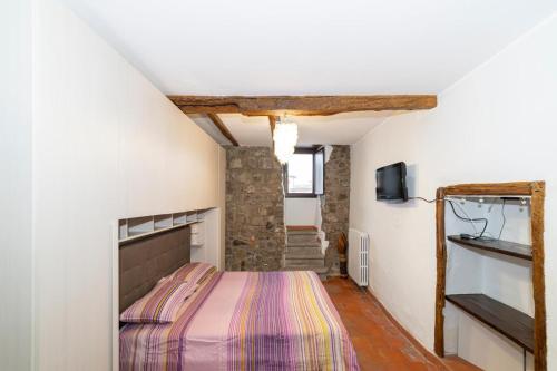 a bedroom with a bed and a tv on a wall at La Casetta al Corso in Montefiascone