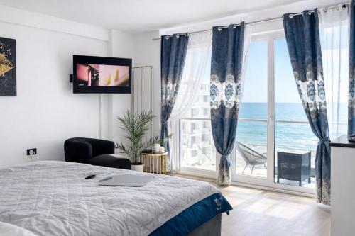a bedroom with a bed and a large window with the ocean at Waves 342 Infinity in Mamaia Sat/Năvodari