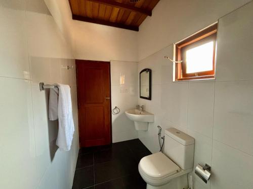 a bathroom with a toilet and a sink and a window at Sonic Villa,Beruwala in Beruwala