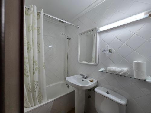 a white bathroom with a sink and a shower at Pensión La Unión in Trevías