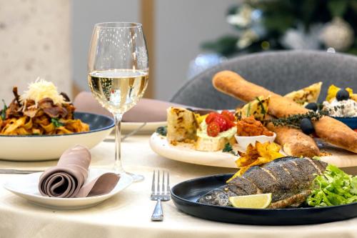 a table with plates of food and a glass of wine at Pirin Sense Apartment Complex in Bansko