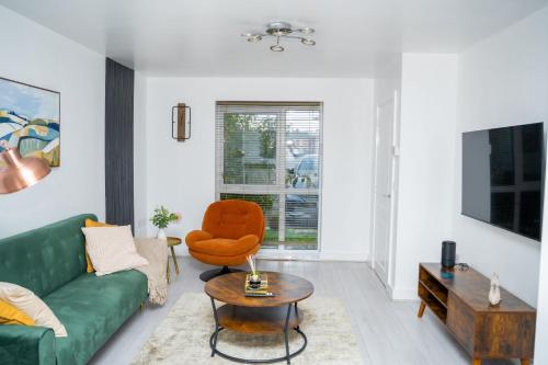 a living room with a green couch and a chair at Modern 2BR Home in Manchester in Manchester