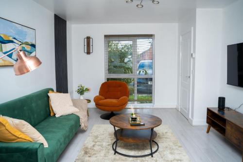 a living room with a green couch and an orange chair at Modern 2BR Home in Manchester in Manchester