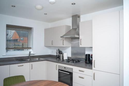 a kitchen with white cabinets and a wooden table at Modern 2BR Home in Manchester in Manchester