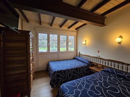 a bedroom with two beds and a window at Pensión La Unión in Trevías