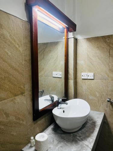 a bathroom with a white sink and a mirror at Sigiriya Yahana in Sigiriya