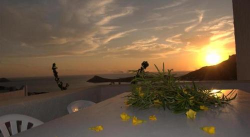 a table with flowers on it with the sunset in the background at Afroditi Hotel in Masouri
