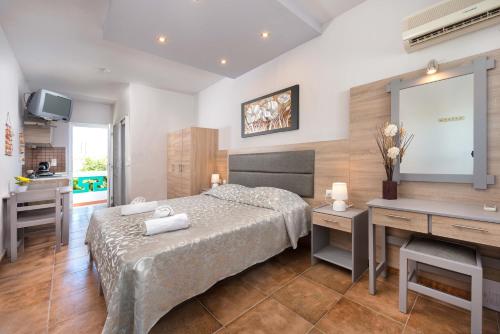 a bedroom with a bed and a desk and a kitchen at Melody Studios Faliraki in Faliraki