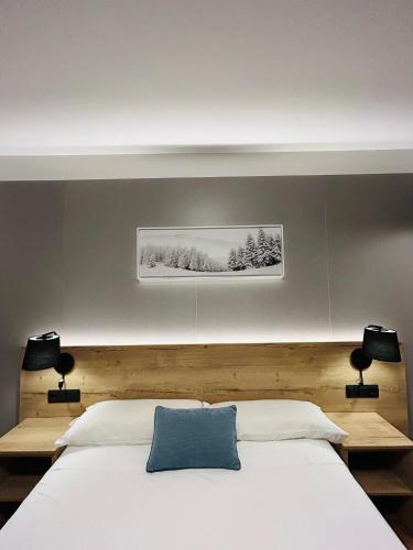 a bedroom with a bed with a blue pillow on it at Hotel La Bonaigua in Vielha