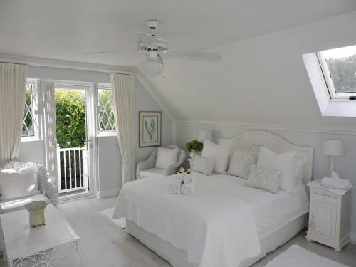 a white bedroom with a white bed and a chair at Riverlea in Cape Town