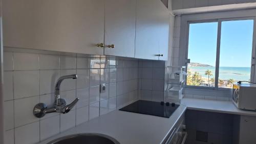 a white tiled kitchen with a sink and a window at Frontal con vistas in Benicàssim