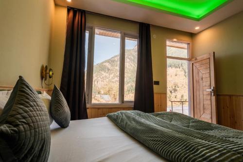 a bedroom with a large bed with a large window at Sunrise Farm Stays in Jibhi