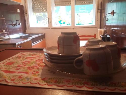a kitchen with a stack of plates and cups on a table at Guest House Anna Vendégház in Svetozar Miletić