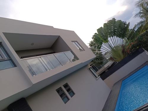 a building with a swimming pool next to a palm tree at Sunset Haven in Flic-en-Flac