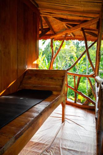 a wooden bed in a room with a window at La Capanna Sumatra Ecovillage in Timbanglawang