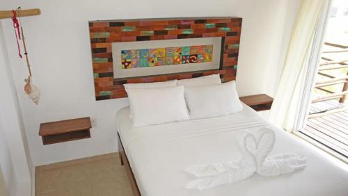 a white bed in a room with a brick wall at El Fuerte Beach Apartments in Mahahual