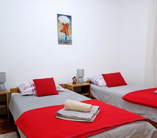 two beds in a room with red blankets on them at Sunstation in Šarengrad