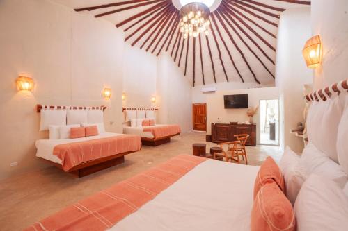 a large room with two beds and a tv at Alquimia Hotel Boutique in Tulum