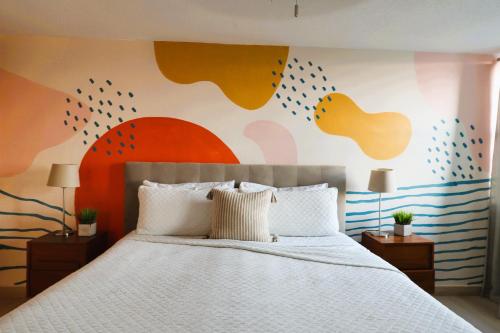 a bedroom with a white bed with a colorful wall at Attractive Penthouse in Isla Verde in San Juan