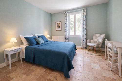 a bedroom with a blue bed and a chair at Ferme du Grand Breton - Chambres et Table d'hôtes in Beaumont-de-Lomagne