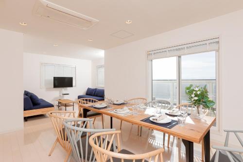 a dining room with a wooden table and chairs at ファブール葉山別邸 海岸まで徒歩15秒の富士山と夕陽を望む海辺のお家 in Hayama