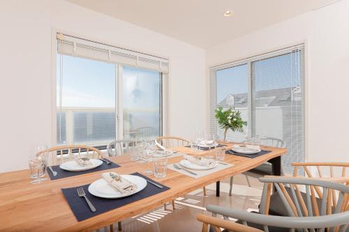 a dining room with a wooden table and chairs at ファブール葉山別邸 海岸まで徒歩15秒の富士山と夕陽を望む海辺のお家 in Hayama