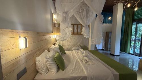 a bedroom with a large white bed with green pillows at Rawana River Edge in Ella