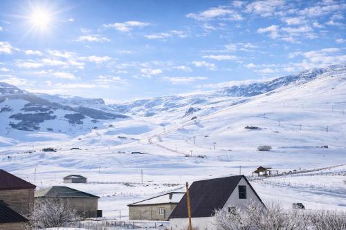 a snow covered hill with a house and a horse on it at Shahdag Cozy House in Qusar