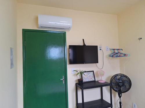 a green door in a room with a tv and a fan at Quarto TOP perto do Centro e Praias AR TV Wifi Cozinha Lavadora in São Luís
