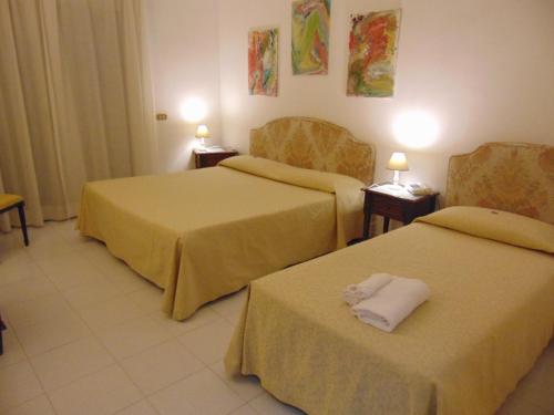 a hotel room with two beds and two chairs at Hotel Calla' in Policoro