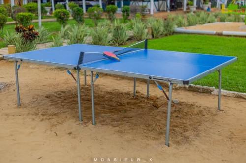 un tavolo da ping pong blu con una racchetta sopra di Songon Park Resort a Songon-Agban