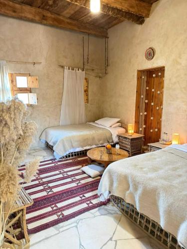 a bedroom with two beds and a table in it at Tanirt ecolodge in Siwa
