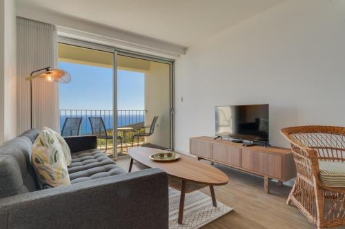 a living room with a couch and a television at Pearl Retreat by Holiday Rental Madeira in Câmara de Lobos