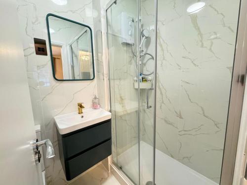 a bathroom with a sink and a shower with a mirror at New Kings Cross Apartment in London