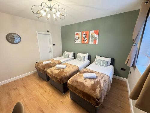 a room with three beds and a clock on the wall at New Kings Cross Apartment in London