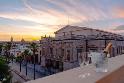 Una botella de champán y dos copas de vino en una repisa en Hotel Roma, en Durango
