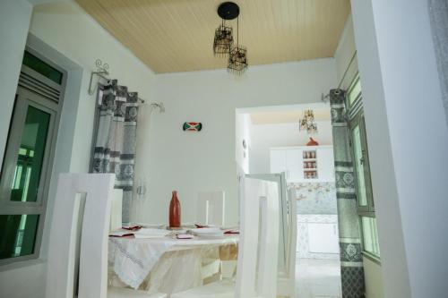 a white dining room with a table and a window at The city Block Apartment in Bujumbura