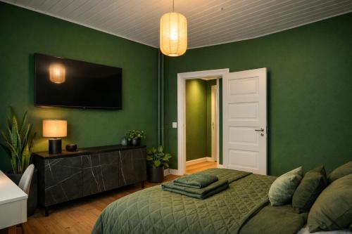 a green bedroom with a bed and a flat screen tv at Danmarksgade Rooms in Aalborg