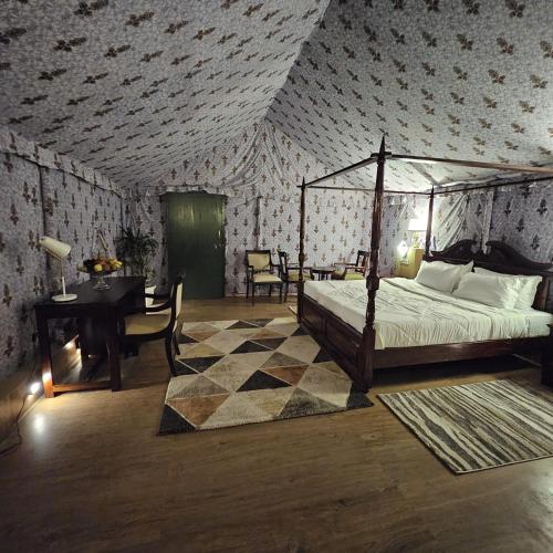 a bedroom with a bed and a table and a desk at Tiger Woods Ranthambore in Sawāi Mādhopur