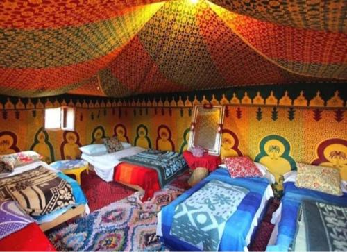 a bedroom with four beds and a colorful ceiling at Desert Berber Fire-Camp in Merzouga