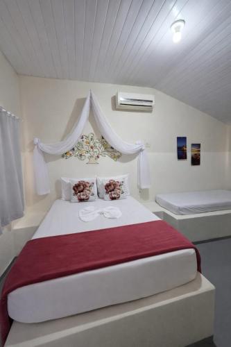a white bedroom with a large bed with a red blanket at Pousada 2 Rios Comfort in Barra do Garças