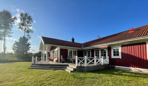 a red and white house with a deck at Aspudden en pärla i Sörmland in Vingåker