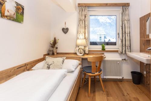 a bedroom with a bed and a desk and a window at Neuhof Appartements in Maishofen