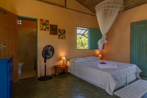 a bedroom with a bed and a window and a fan at Chalé Pé de Araçá - Massarandupió in Entre Rios